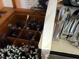 a person holding a knife in their hand in front of a drawer full of silverware