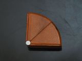 brown leather triangle with a white button on a black surface