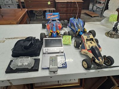 une table sur laquelle se trouvent un ordinateur portable, une télécommande et des petites voitures