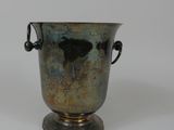 un vase en argent posé sur une surface blanche