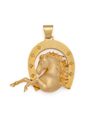 un gros plan d'un pendentif en forme de cheval doré sur fond blanc