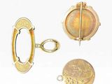 two gold - plated charms and a coin on a white surface