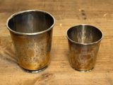 two silver cups sitting on a wooden table next to each other