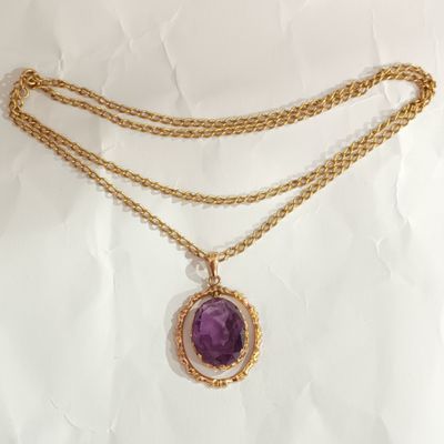 un gros plan d'un collier orné d'une pierre violette