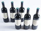 six bottles of wine are lined up in a row on a white surface