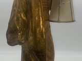 une statue représentant une femme tenant une lampe posée sur une table
