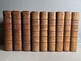 several old books are lined up in a row on a table