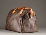 a close up of a brown louis vuitton bag on a gray surface