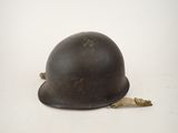 an old helmet is sitting on the ground with a leaf on it