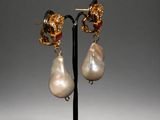 a pair of pearl and gold earrings on a black stand
