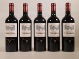 quatre bouteilles de vin rouge sont alignées sur une table