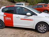 a small white car with a red and white stripe parked in a parking lot