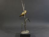 bronze sculpture of a bird perched on a branch