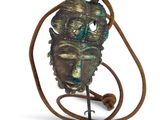 an image of a bronze mask on a stand on a white background