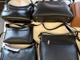 several black leather handbags on a table in a room
