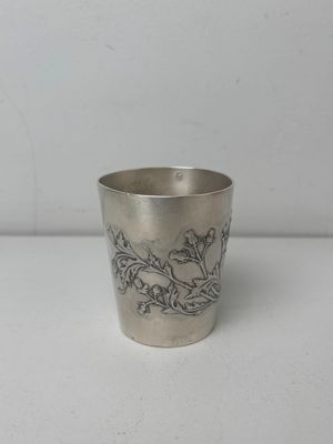 an antique silver cup with a floral design on the rim