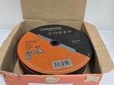 un disque orange et noir dans une boîte en carton posée sur une surface blanche