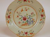 une assiette ornée d'un motif floral, posée sur un socle