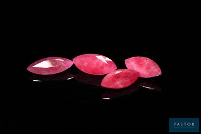 a group of three pink gems sitting on top of a black surface