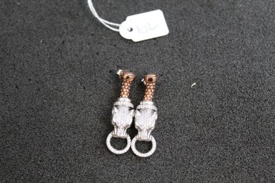 paire de boucles d'oreilles plaquées argent et or rose sur un fond noir