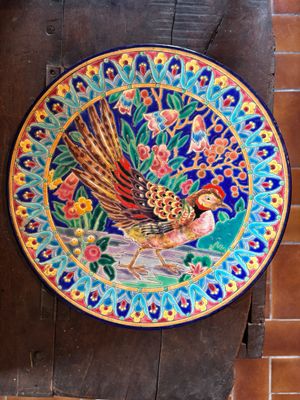 a colorful plate with a bird on it on a table