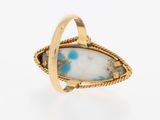 a close up of a gold ring with a white and blue stone