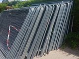 un tas de grillage métallique appuyé contre une clôture