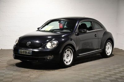 une photo d'une Coccinelle Volkswagen noire garée dans un garage