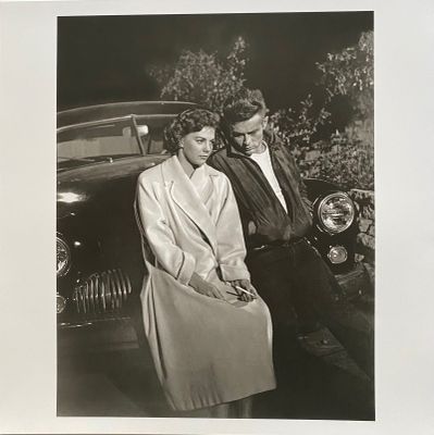 photographie en noir et blanc d'un homme et d'une femme debout à côté d'une voiture