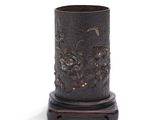 un vase noir orné de fleurs, posé sur un socle en bois