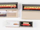 trois trains miniatures dans une boîte, posés sur une surface blanche