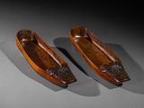 pair of carved wooden canoes on a gray surface