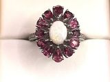 an image of a ring with a white oplite surrounded by pink sapphires