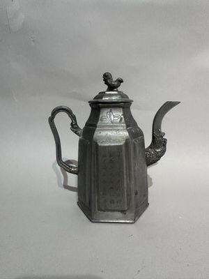 a silver tea pot with a bird on it