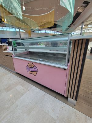 une vitrine rose sur laquelle sont disposés des beignets, dans un immeuble