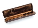 a brown case with a pen in it on a white surface