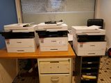 de nombreuses imprimantes posées sur un bureau dans une pièce