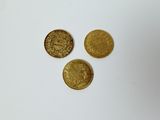 a close up of three gold coins on a white surface