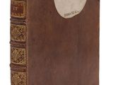 un vieux livre à la couverture brune posé sur une surface blanche