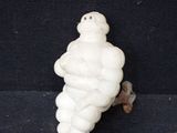 une petite figurine blanche représentant un homme corpulent sur fond noir