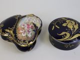 deux boîtes noires et dorées ornées de motifs floraux sur un fond blanc
