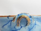 a blue bowl with a brown handle on a white surface