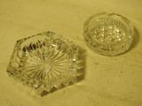 pair of clear glass ashtrays on a table with a cloth