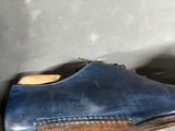 pair of blue leather shoes with brown soles sitting on top of a gray surface