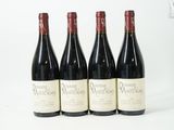 quatre bouteilles de vin sont alignées sur une surface blanche