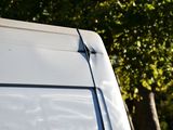 a white van parked in a parking lot with trees in the background