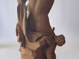 statue of a man sitting on a rock with a bird in his hand