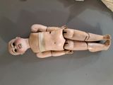 une poupée en bois posée par terre, entourée d'un bandage