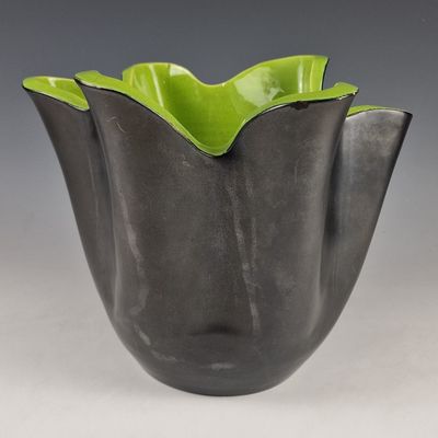 a close up of a black and green vase on a table