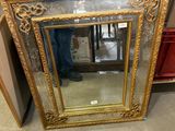 a gold framed mirror sitting on the floor in a store